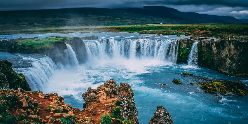 A picture of a massive waterfall in Jamaica surrounded by lush greenery