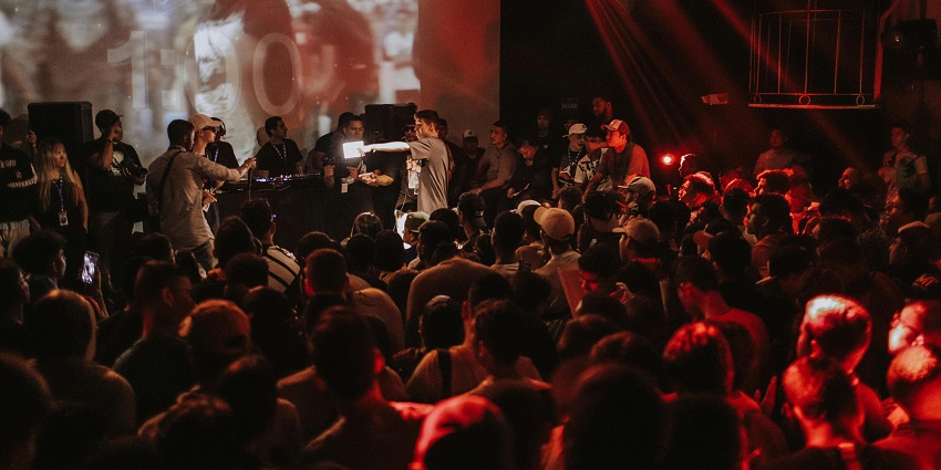 A crowd of people and a musical band performing with a screen in the background.