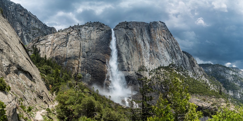 Yosemite Falls, one of the best waterfalls in California, is surrounded by rocky cliffs.
