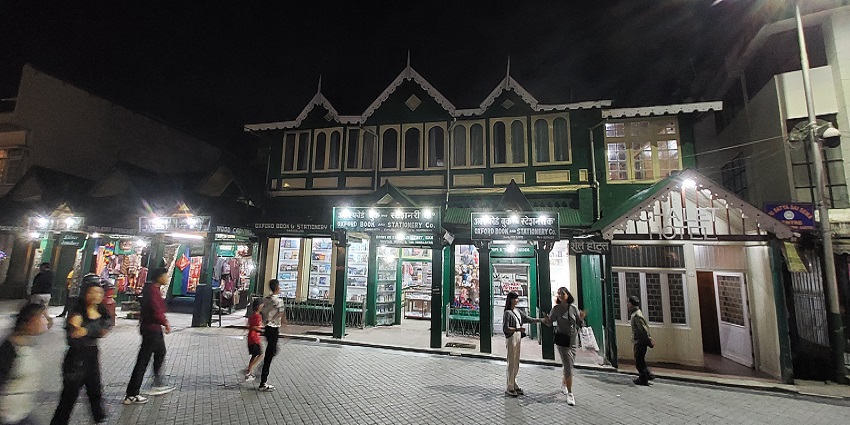 A picture of a central open space at Darjeeling Mall with shops and mountain views.
