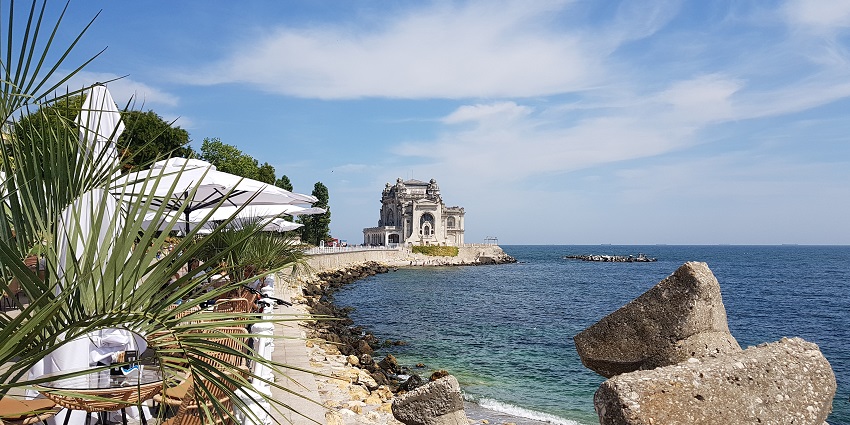 Cazino with a stony shoreline, a stone structure beside the sea, a table and chairs.
