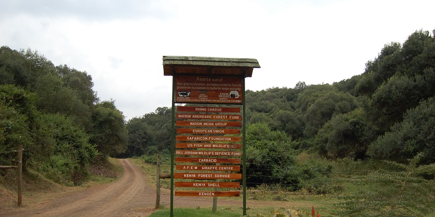 Treetops entrance to Aberdare National Park with a board with multiple signages on it.