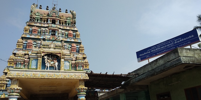 Gopuram of Kanjanur temple detailed architecture and people and an auto near the gates.