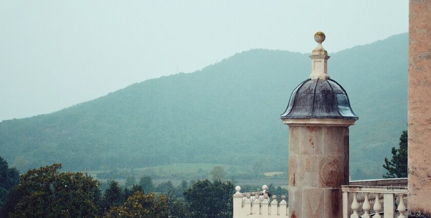 An image of a tower from the 19th century has a domed rooftop and can be seen from a hill.