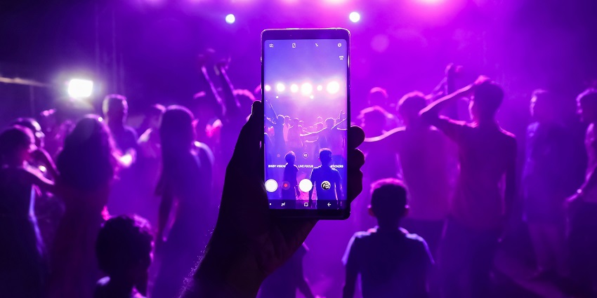 A club with purple lights where musicians are performing on stage and audience is listening.