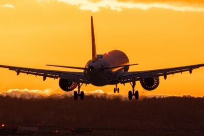 An image of a serene view of an aeroplane flying during golden sunset hour