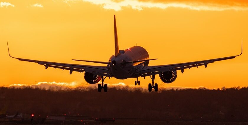 An image of a serene view of an aeroplane flying during golden sunset hour