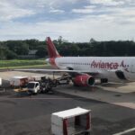 An Avianca Costa Rica plane parked at El Salvador International Airport under a clear sky.