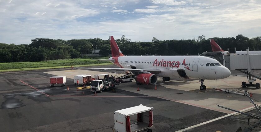 An Avianca Costa Rica plane parked at El Salvador International Airport under a clear sky.