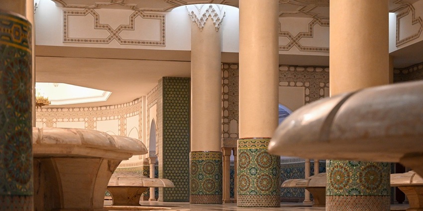 An inner view of a mosque where green carpets are placed and the rooms are decorated well.