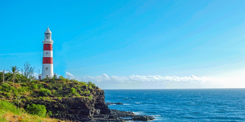 Albion in Mauritius with a lighthouse on the cliff by the sea and big stones in the sea.