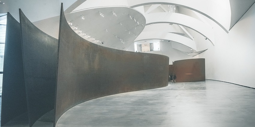An image of an art museum gallery with various paintings displayed on white walls.
