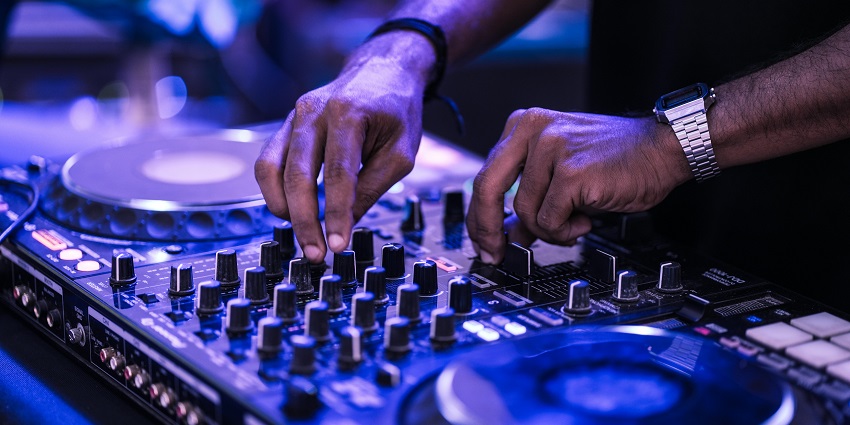 A person wearing a watch in one hand operating the music keyboard and flipping switches.
