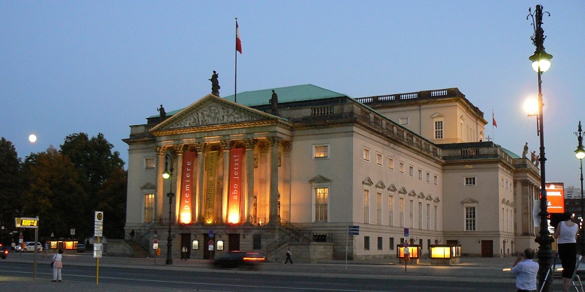 Outside the Staatsoper Berlin Opera with its structure and people passing by at twilight.