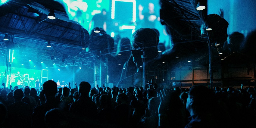 A crowd of people walking down a lively night street, surrounded by neon-lit nightclubs and bustling nightlife.