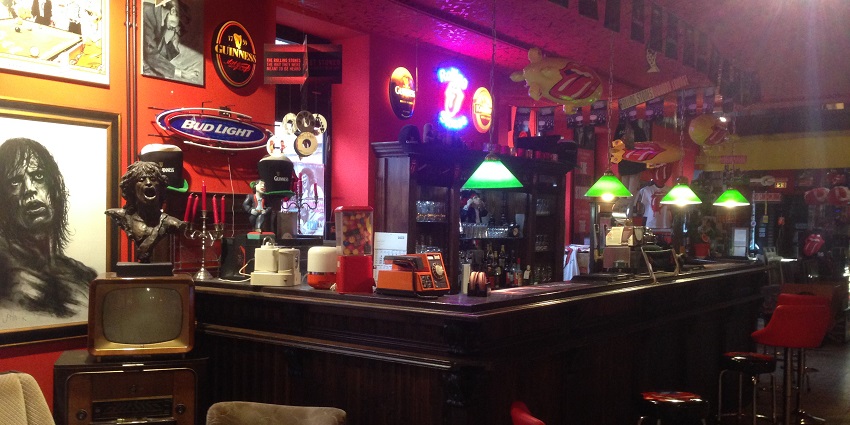 Inside a bar with stone sculptures, wall paintings and small green lamps, showing Warsaw nightlife.