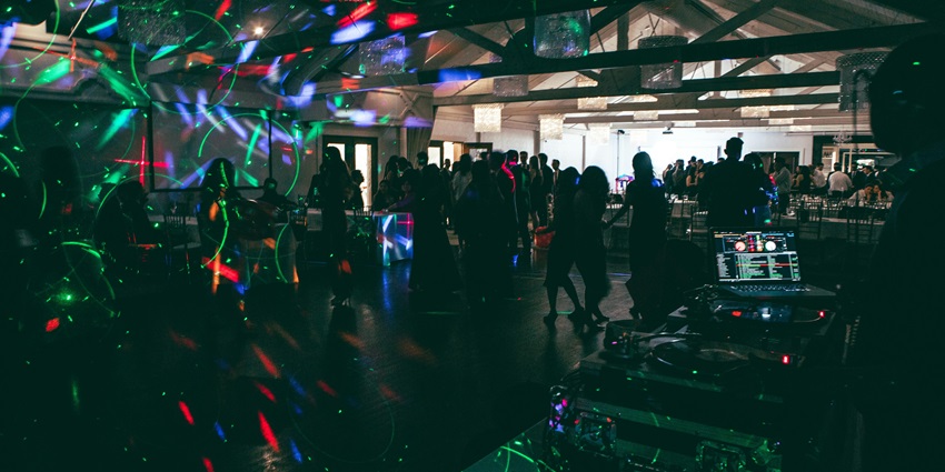 Night club with people dancing, unique neon lighting, disco lasers and a DJ playing