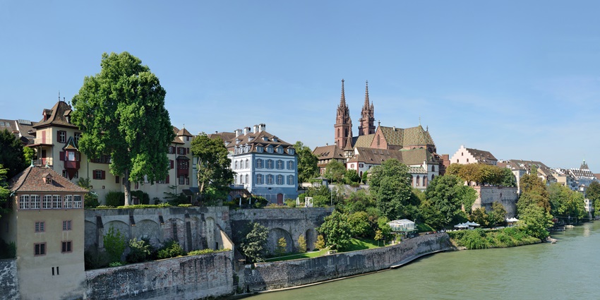 A picture of a river bank with traditional Swiss architecture buildings and greenery all around