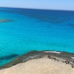 Several small shacks are located near the pristine beach, surrounded by clear water.