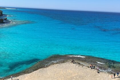 Several small shacks are located near the pristine beach, surrounded by clear water.