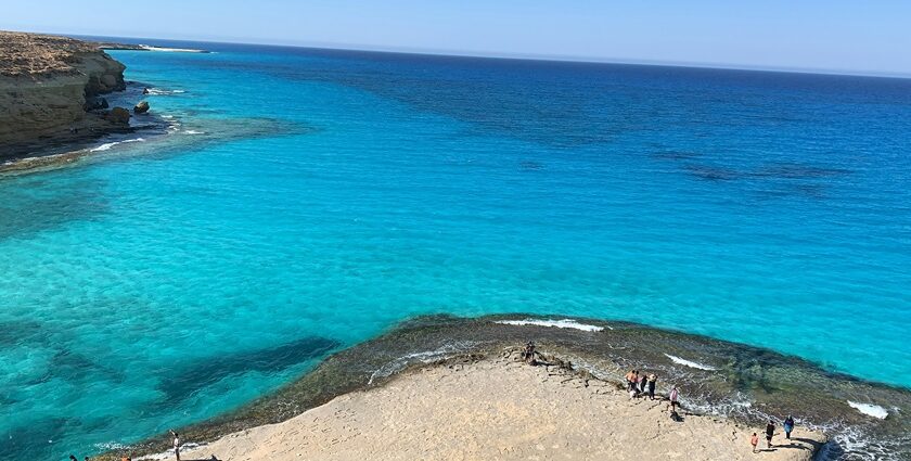 Several small shacks are located near the pristine beach, surrounded by clear water.