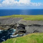 An image of green grass on rocky mountain near a beach, highlighting Beaches in Ireland