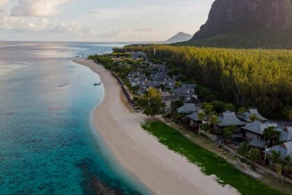 A pristine beach with white sand alongside whose shore there are several boats present.