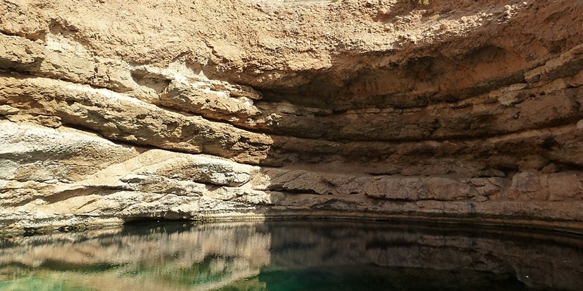 Natural limestone sinkhole filled with emerald-green water.