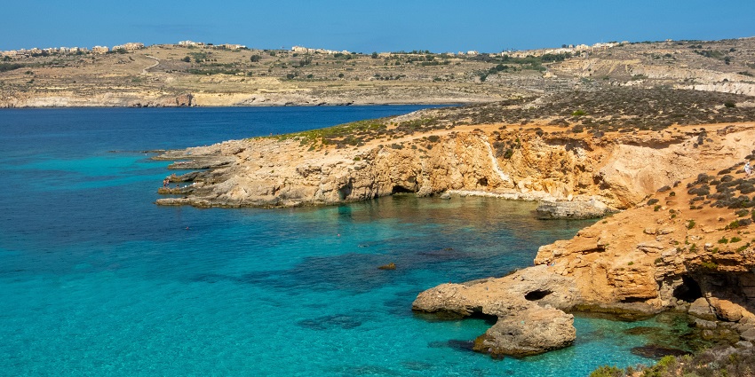 The Blue Lagoon is surrounded by a huge yellow stone with small holes and damages.