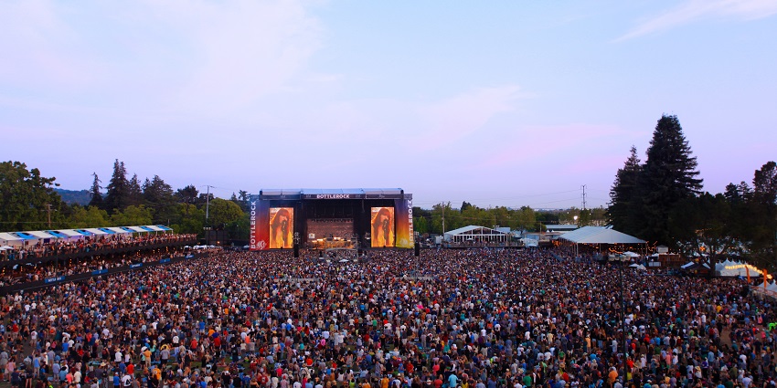 Festival goers enjoying live music at BottleRock Napa Valley, with views of the vineyards.