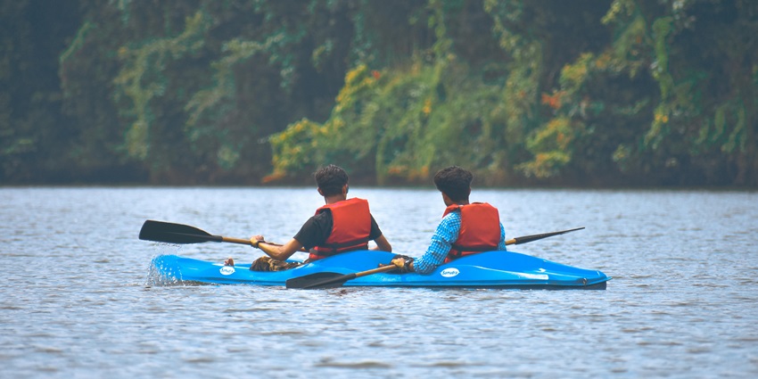 An image of two men in a kayak in the lake surrounded by dense forests in Boundary Waters.