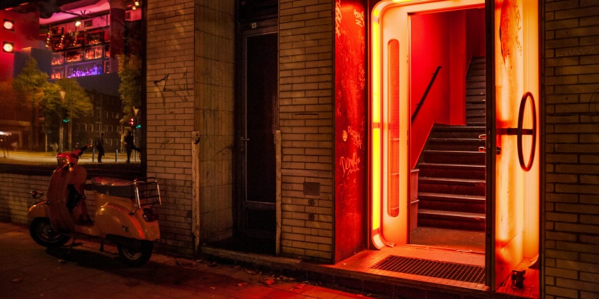 Entrance to the bar with open door yellow walls, orange lighting and a scooter parked