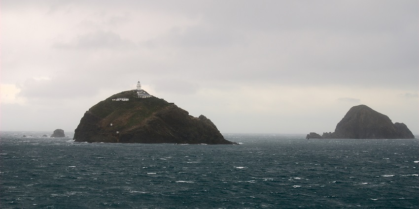 Two small rocky islands of the brothers islands with white buildings on top of one