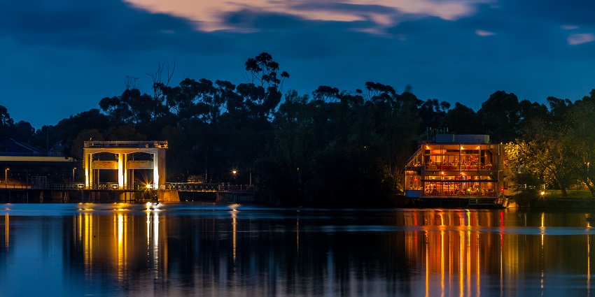 Cafe by the river with the lights reflecting on the waters at night and trees behind it
Viewers of this file can see comments and suggestions