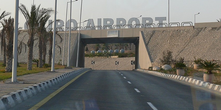 Cairo airport showing the entrance road, the sign and palm trees on the sides