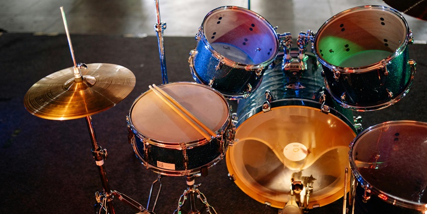 A set of drums inside a jazz club with cymbals, snare drums, pair of drumsticks on a drum