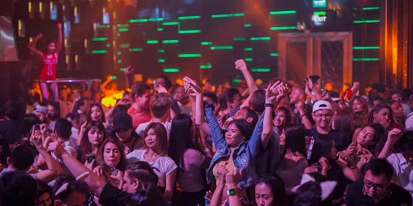 A crowded nightclub with people enjoying the music, colorful lights, and a vibrant party atmosphere.
