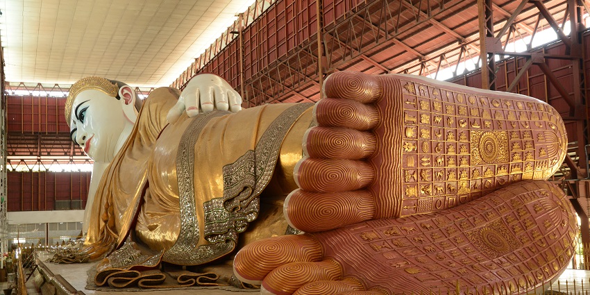 Reclining Buddha statue inside a large pagoda, must-visit in Yangon travel guide.