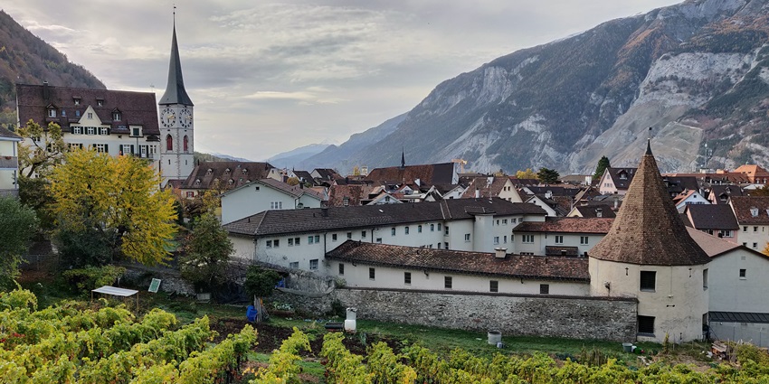 A picture of the scenic town of Chur with historical buildings and views of mountains in the background