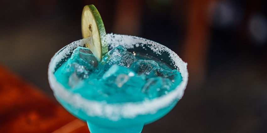 A blue lagoon drink - with a slice of lime on a wooden table