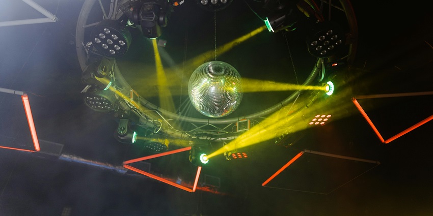 A disco ball hanging from the ceiling and encircled with club lights and cameras, showing Warsaw nightlife.