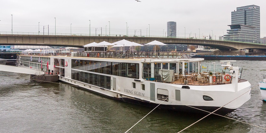 Cruise on the Rhine River under the bridge with tall buildings visible from a distance.