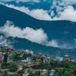 A wide view of Darjeeling shows a massive Kanchenjunga mountain in the background.