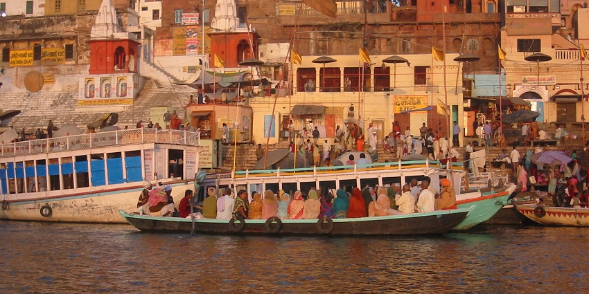 A group of women sit on a boat on the banks of the Dashashwamedh Ghat, suggested by Varanasi Travel Guide.