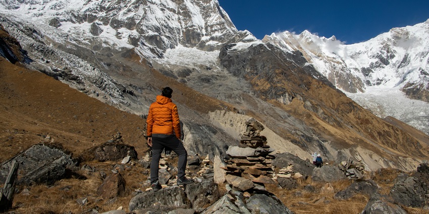 Image of a man hiking in mountains covered by snow and clear blue sky