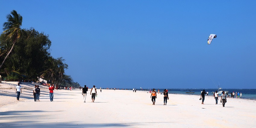 People are enjoying various activities on the Diani beach, which includes parasailing