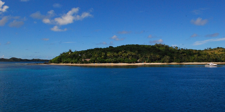 Clear blue waters near Nanuya Island, a speed boat on the far right in Yasawa Islands, one of the best things to do in Fiji.