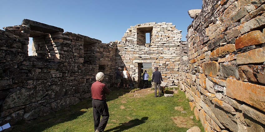 Tourists are visiting the ruins of the Hvalsey Church on a clear sunny day in Greenland.