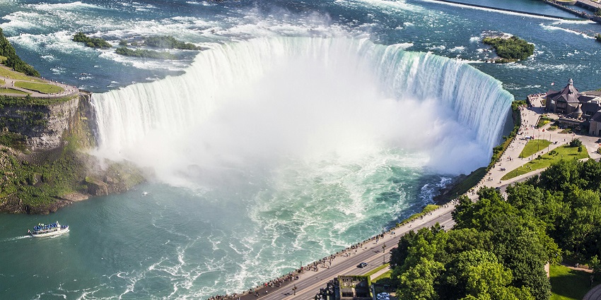 Niagara Falls from the top with the roads, people watching and surrounded by greenery.