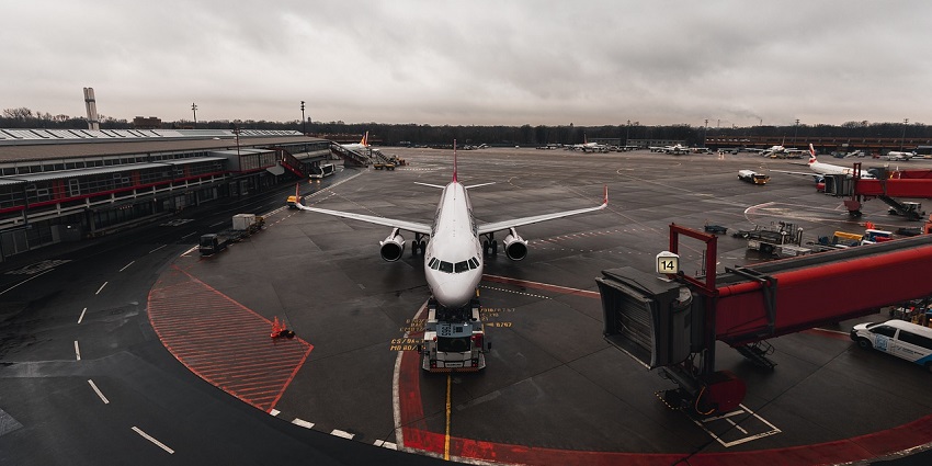 A white airplane parked on the tarmac at an airport, set against a bright blue sky.